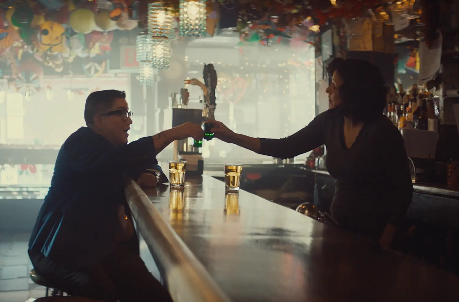 Lea DeLaria and Cubby Hole owner Lisa Menichino clink shot glasses together in the colorfully and eclectically decorated lesbian bar Cubby Hole.